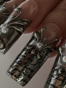 FILIGREE — Détail des arabesques argentées en relief et de la calligraphie noire