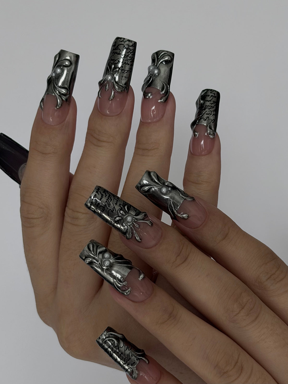 FILIGREE — Mains croisées présentant les motifs argentés et la calligraphie