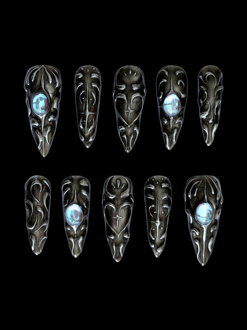 FORGED — Dix press-on Stiletto noirs aux reliefs argentés et cabochons bleus, sur fond noir
