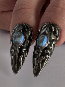 FORGED — Gros plan des cabochons bleus cerclés d’ornements argentés