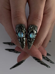 FORGED — Gros plan des deux pouces et des cabochons bleus