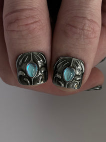 FORGED très court — Gros plan des deux pouces très courts ornés de cabochons bleus