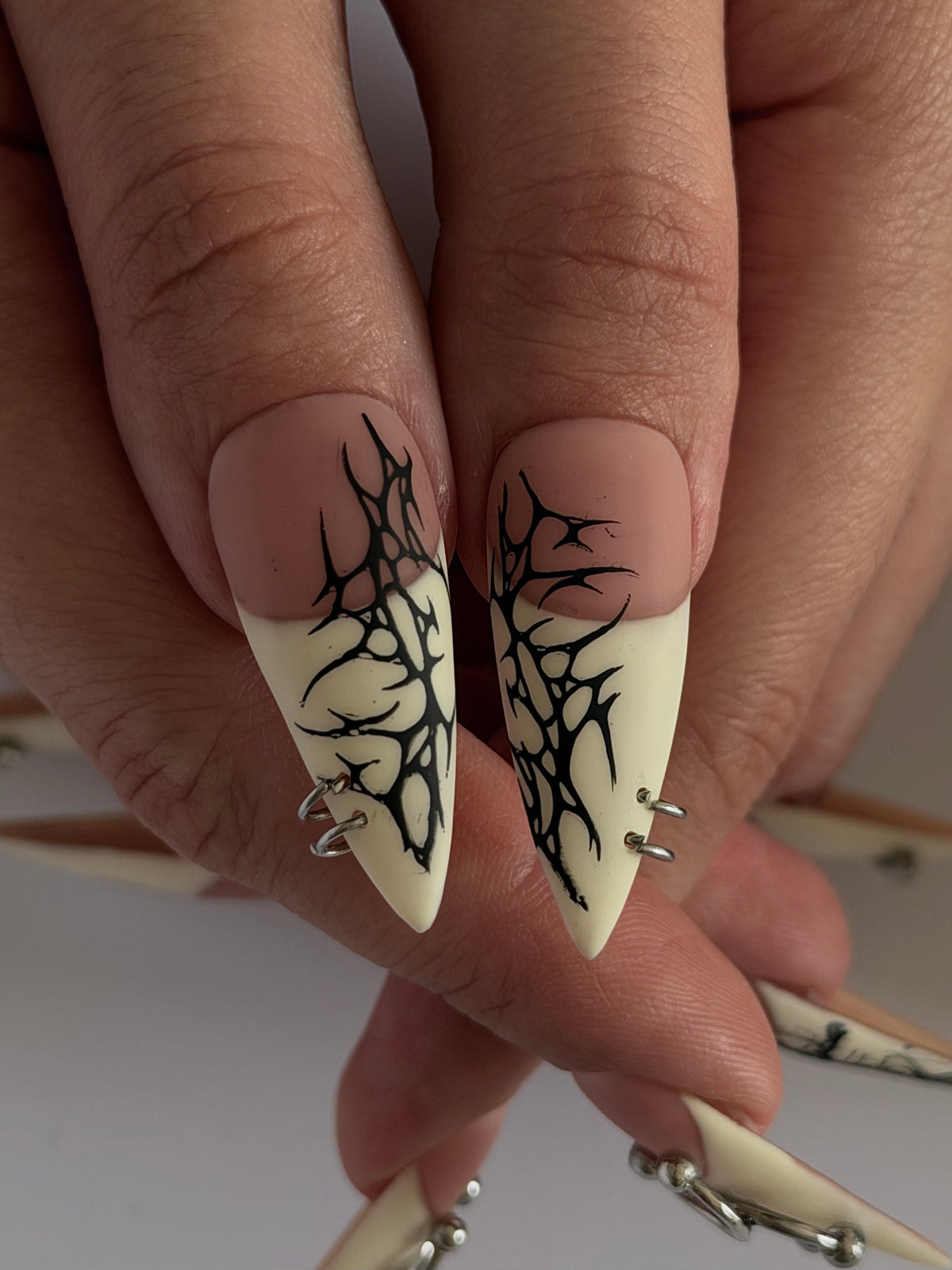 PIERCED — Gros plan des pouces Stiletto aux motifs noirs sur pointes ivoire