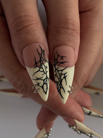 PIERCED — Gros plan des pouces Stiletto aux motifs noirs sur pointes ivoire