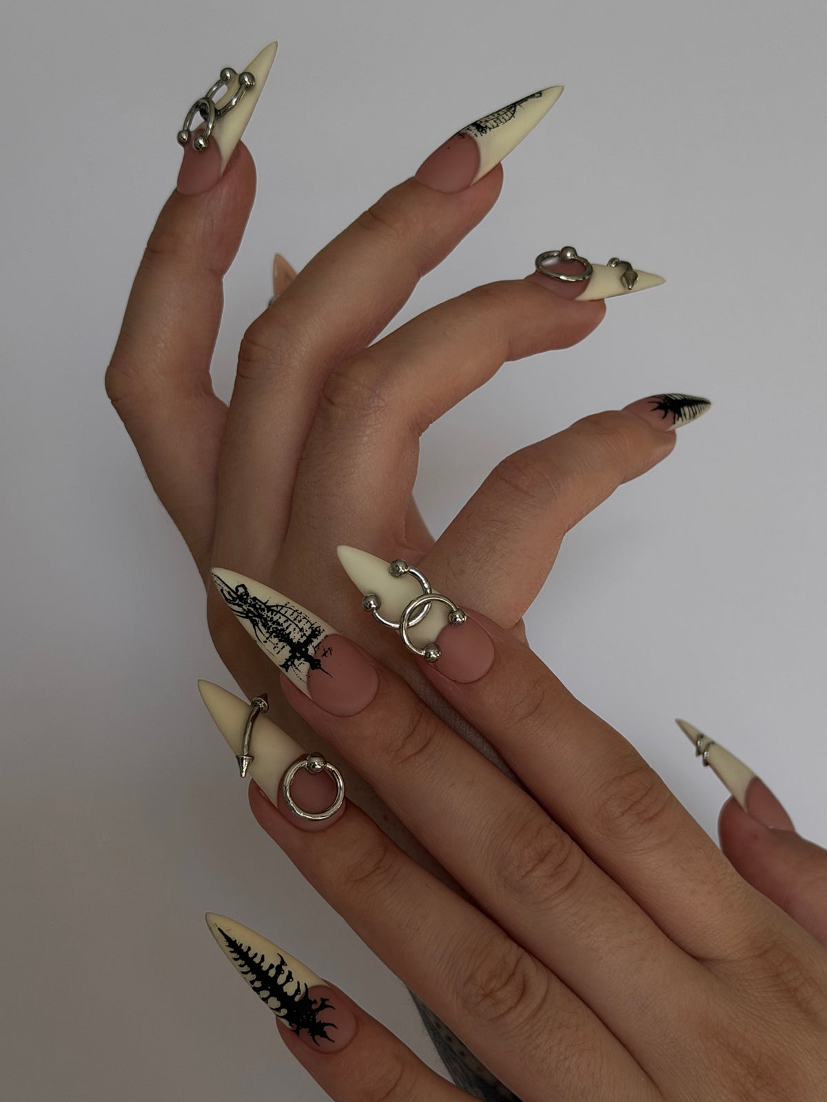 PIERCED — Vue de profil des ongles Stiletto ivoire et nude portés sur deux mains
