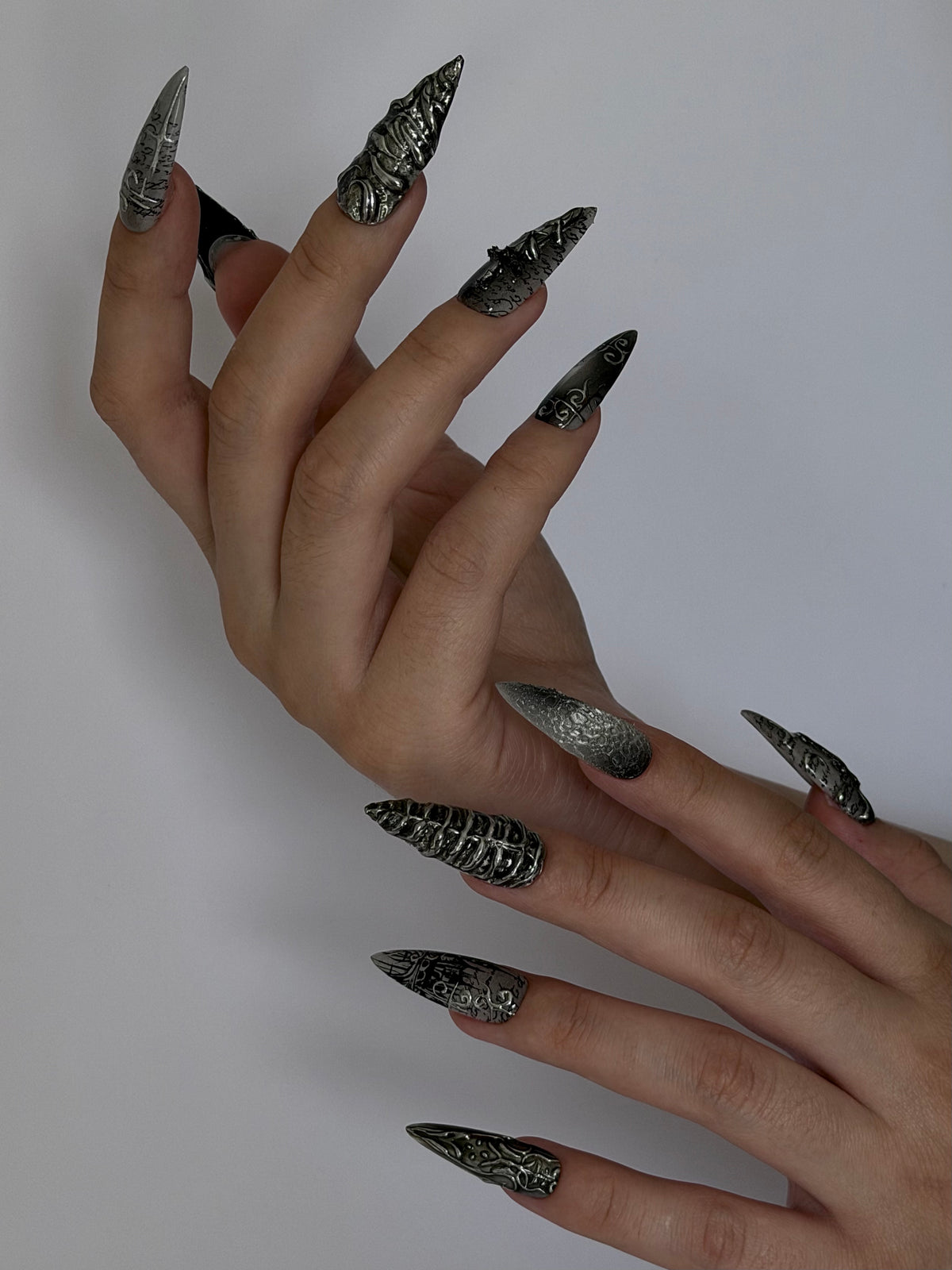 SANCTUM — Vue de profil des ongles Stiletto sculptés portés sur deux mains