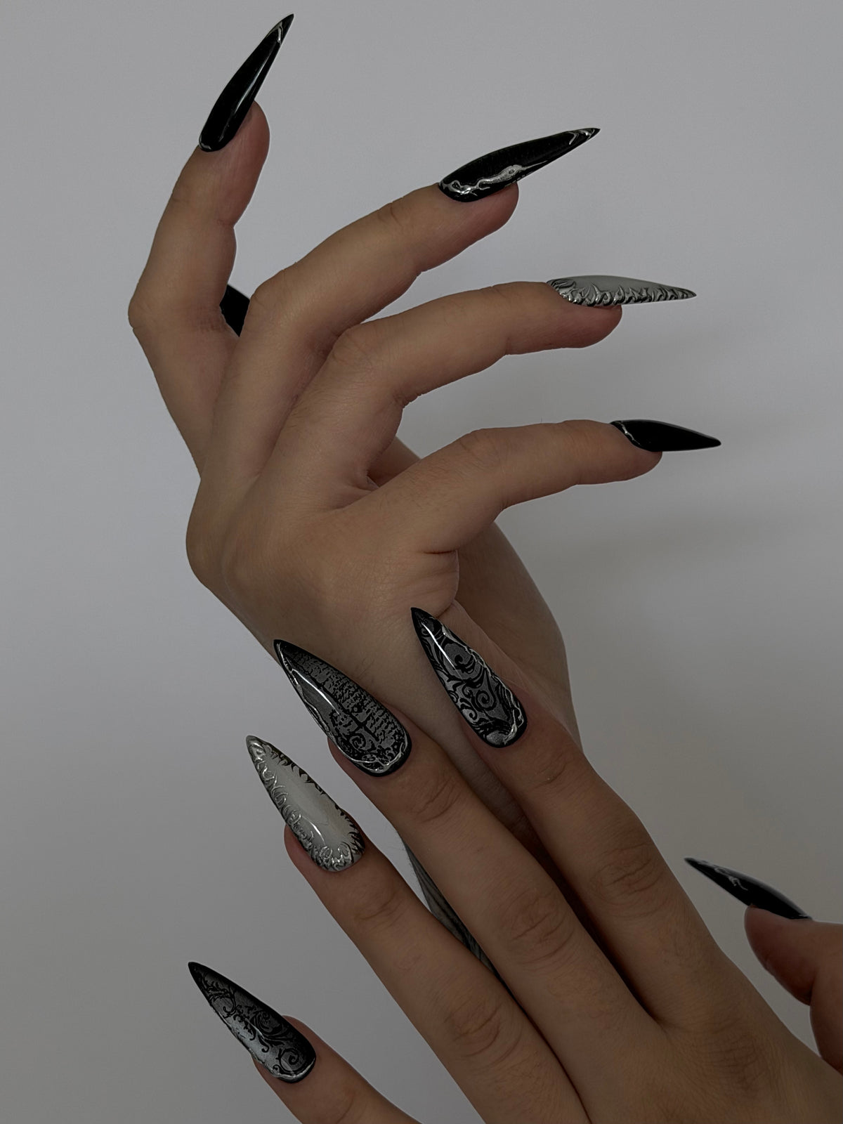 UMBRA — Vue de profil des ongles Stiletto noirs et argentés sur deux mains