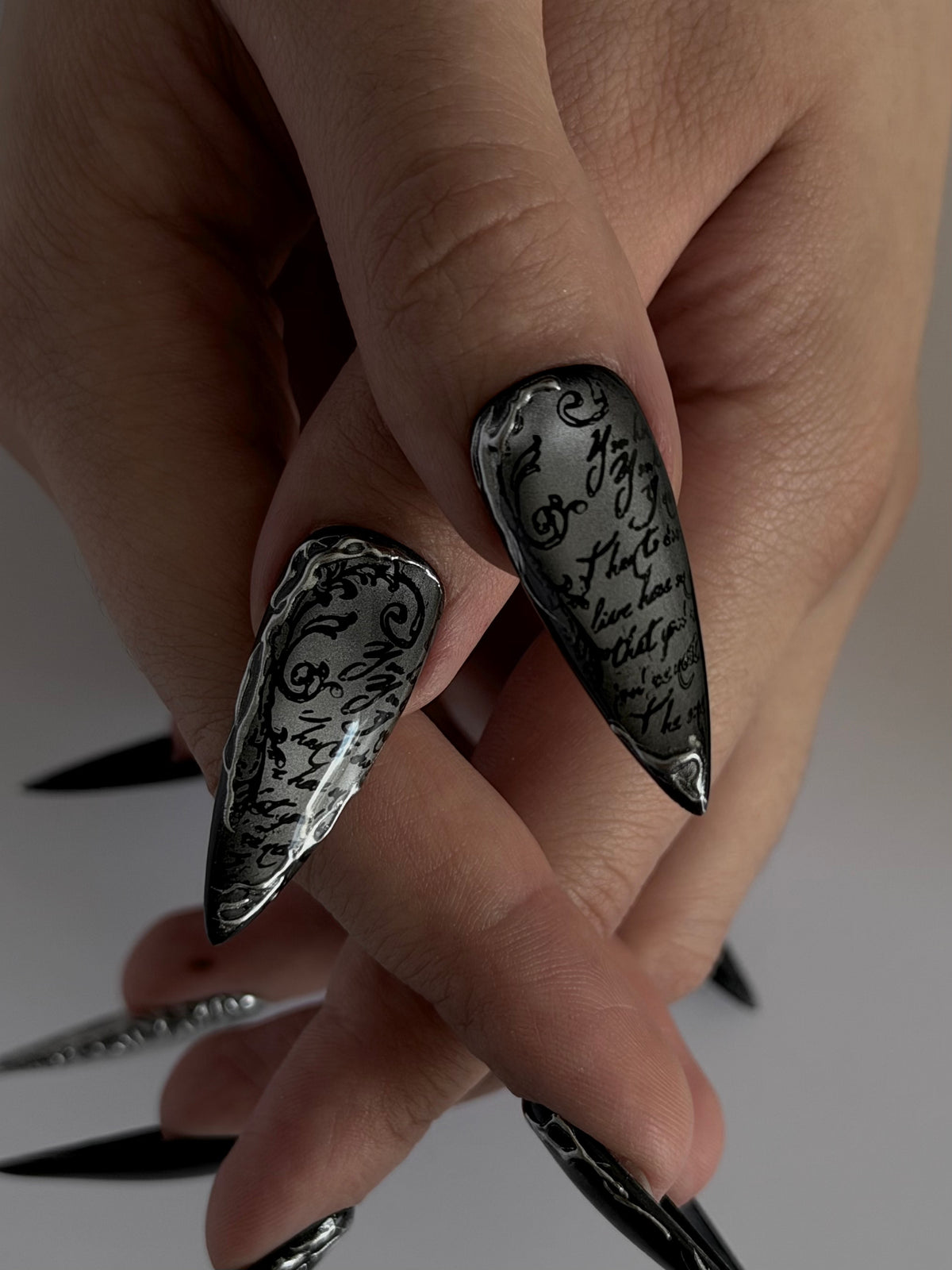UMBRA — Gros plan des deux pouces Stiletto à la calligraphie noire