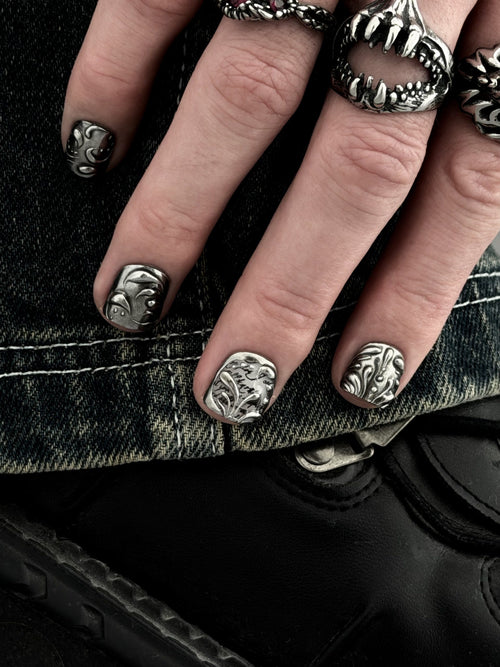 FILIGREE très court — Main posée sur un denim, ongles très courts aux arabesques et à la calligraphie argentées